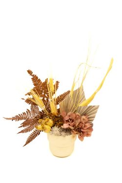 Centro de mesa con base en tono mostazo con flores preservadas amarillas, crema y mostaza