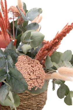 Cesta de mimbre natural con flores rosadas preservadas