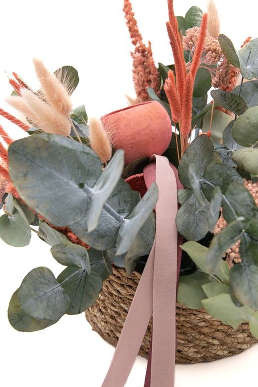 Cesta de mimbre natural con flores rosadas preservadas