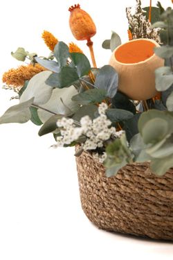 Cesta vintaje de paja natural con alegres flores secas en color naranja