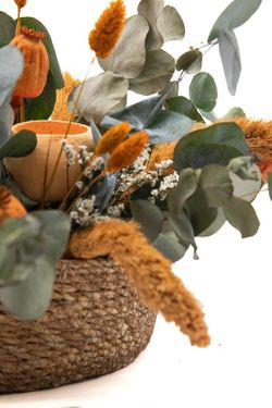 Cesta vintaje de paja natural con alegres flores secas en color naranja