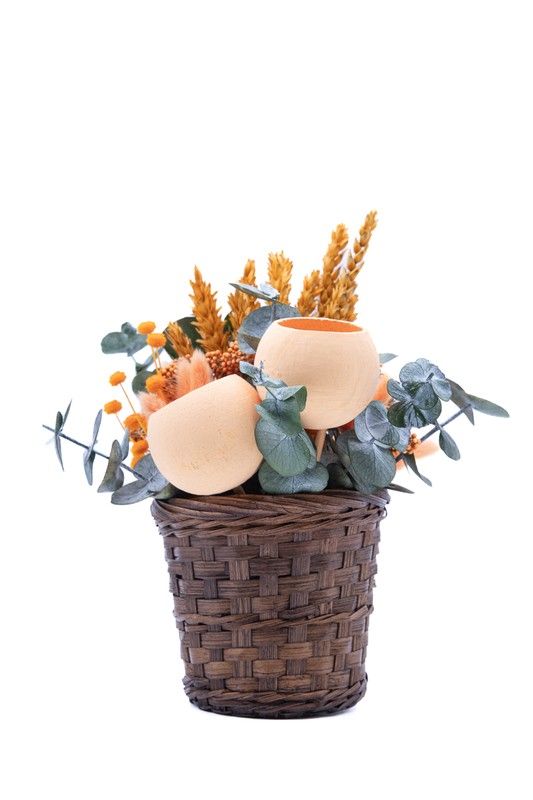 Cesto natural oscuro con flores secas y preservadas en tonos naranjas