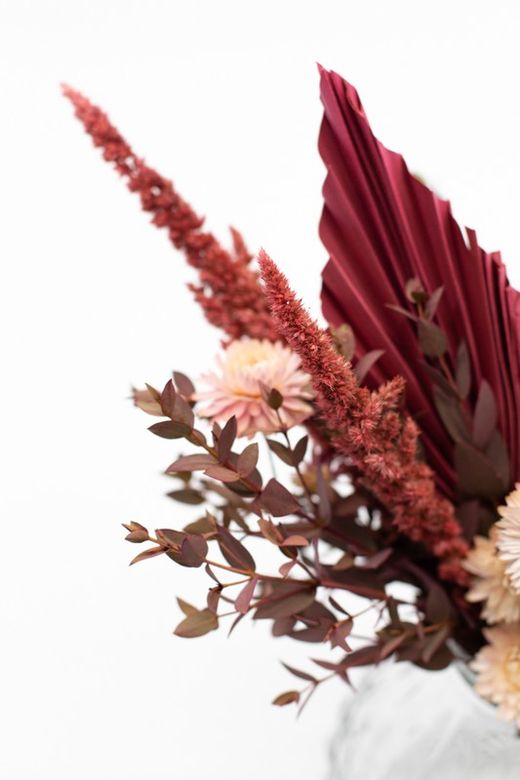 Jarrón vintage con flores preservadas y flores secas en color rosado.